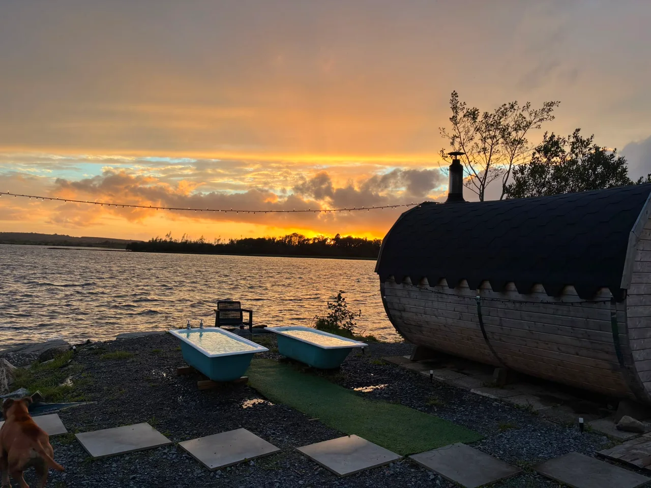 An amber sunset over the sauna, plunge baths and lakeshore