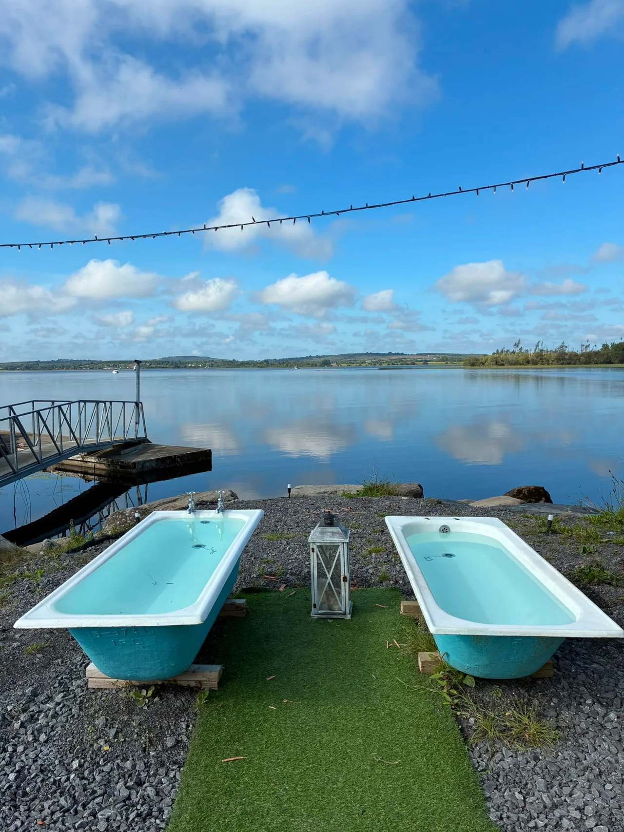 Two blue cold plunge baths overlooking the still lake and harbour jetty