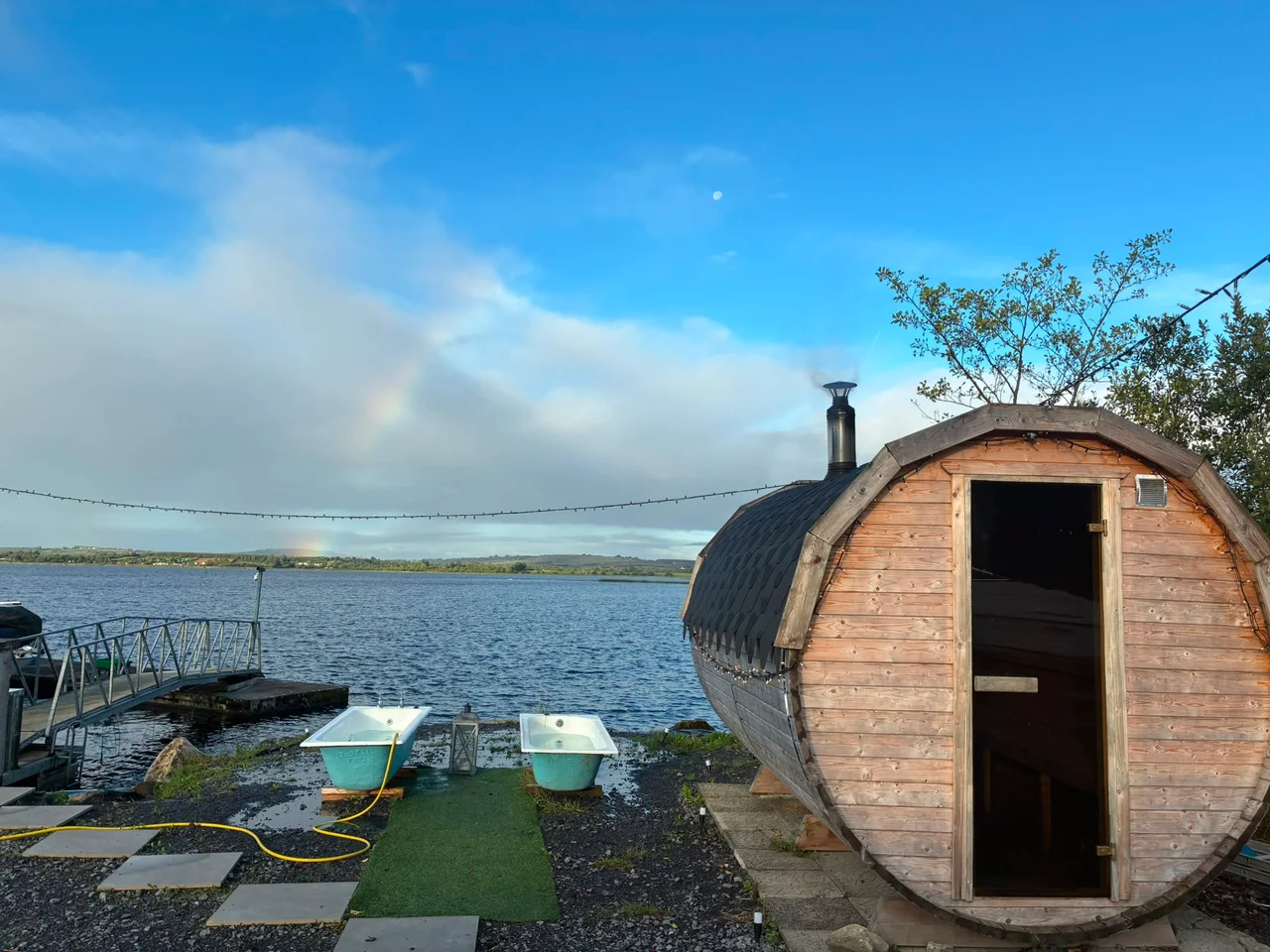A rainbow over the lake beside the timber barrel sauna