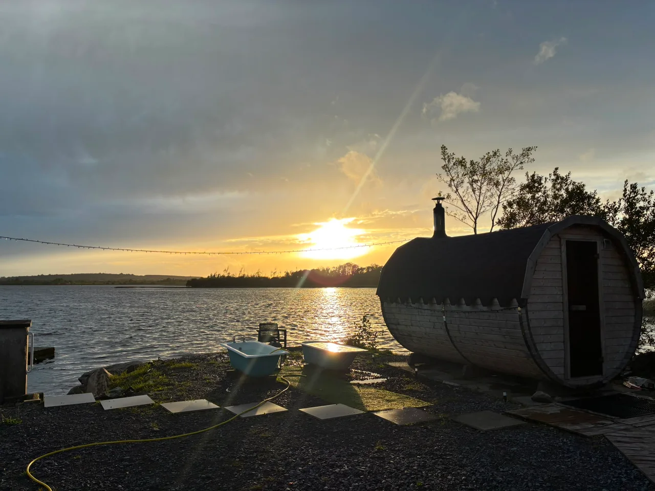 The setting sun reflects across the water beside Celtic Saunas