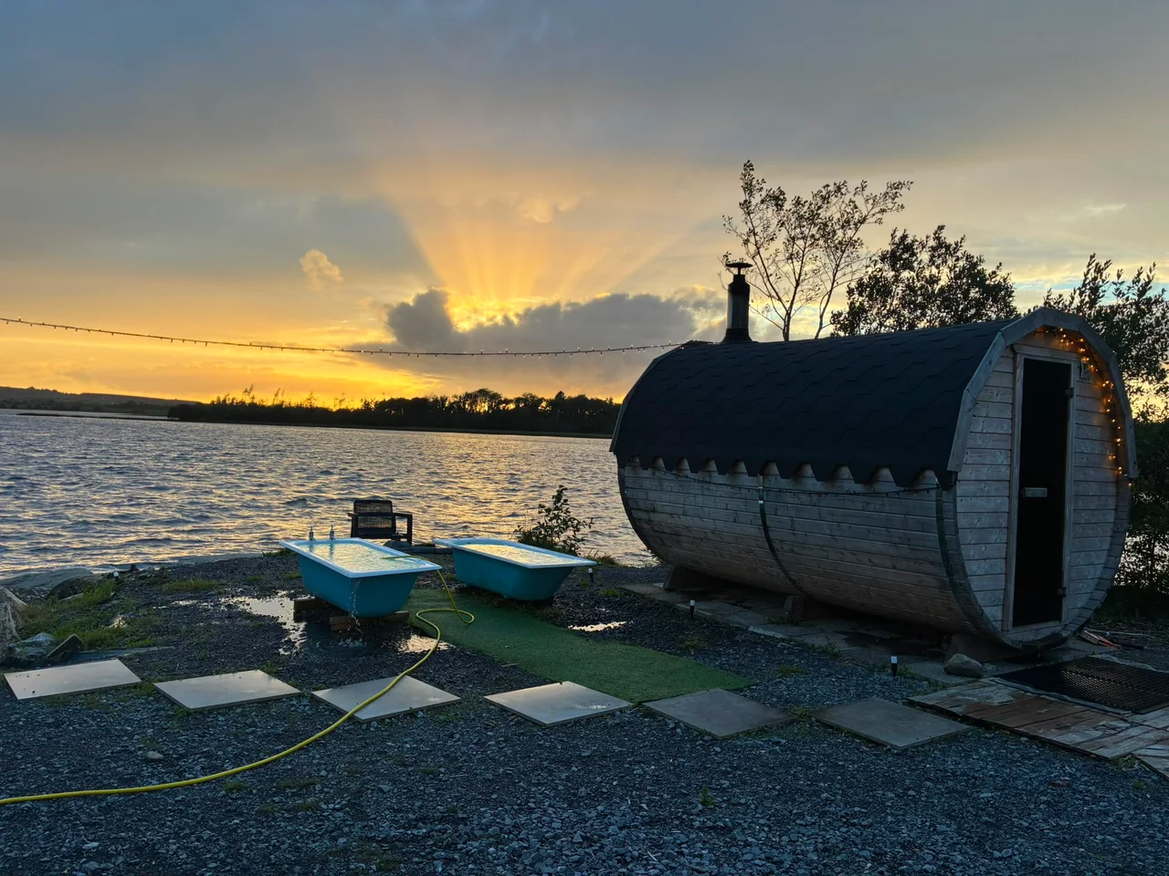 The barrel sauna and blue plunge baths beside the lake at sunset