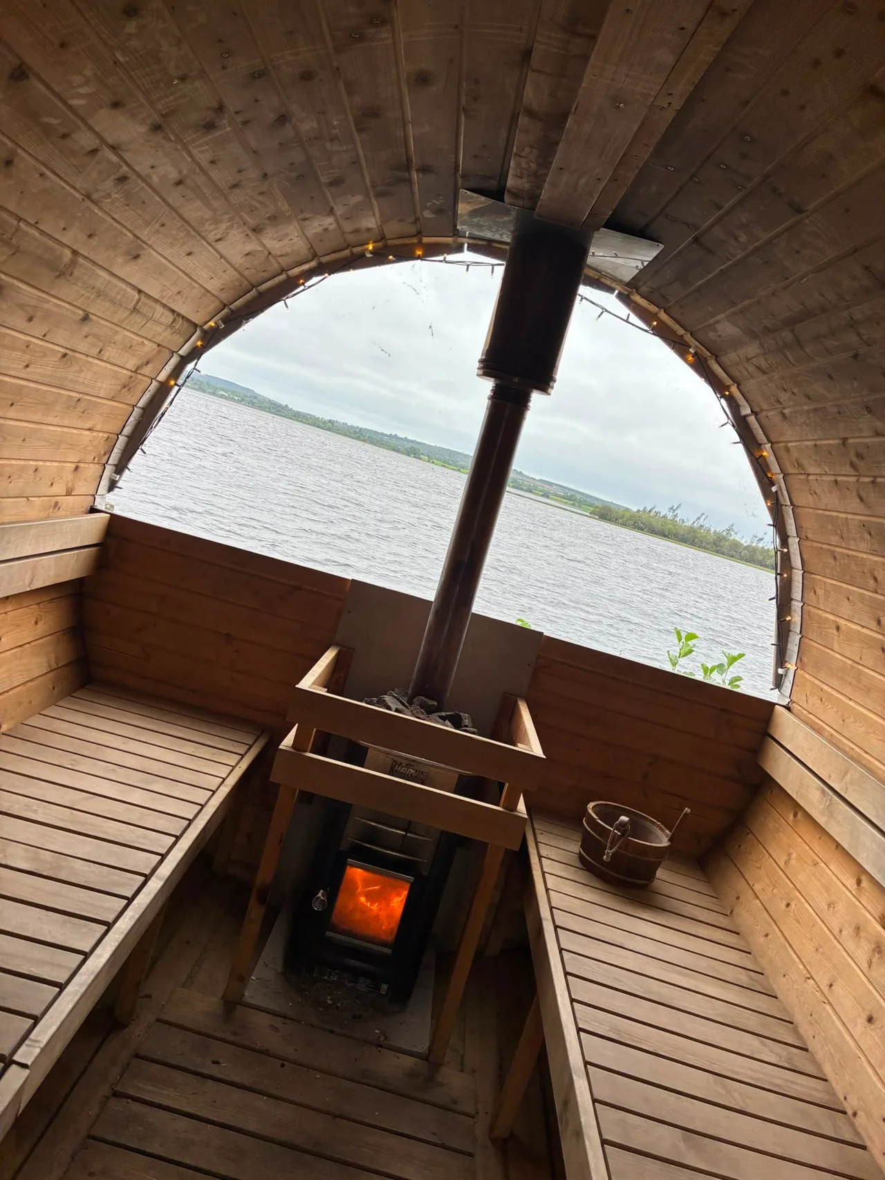 A bright fire burns between the wooden sauna benches