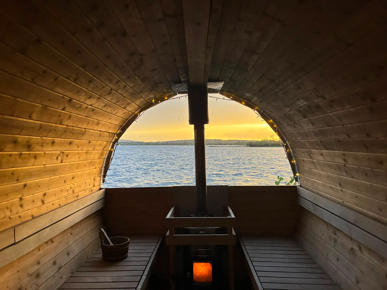 Golden evening light fills the timber sauna with a view across the lake